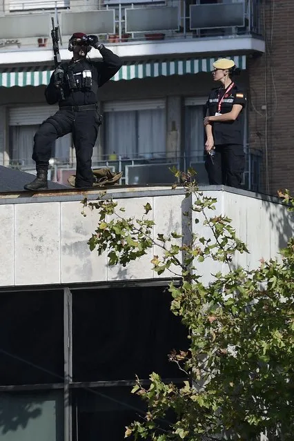 A sniper watches from a roof during the Spanish National Day military parade in Madrid on October 12, 2017. A Spanish Eurofighter jet crashed today after taking part in a military display in Madrid for Spain' s national day, killing its pilot, the defence ministry said. Spain marks its national day under high tension as the country reels from the biggest challenge to unity in a generation with its Catalan region threatening to break away. (Photo by Javier Soriano/AFP Photo)