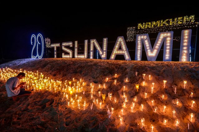 A man lights a candle during a memorial for the 20th anniversary of the Indian Ocean tsunami at a tsunami wave-shaped monument erected for the victims of the 2004 tsunami in Ban Nam Khem, a southern fishing village destroyed by the wave, in Phang Nga province, Thailand, on December 26, 2024. (Photo by Reuters/Stringer)