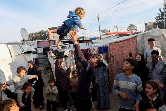 A man throws a child into the air as displaced Palestinians celebrate at a tent camp following a ceasefire between Israel and Hamas, in Deir Al-Balah in the central Gaza Strip, on January 19, 2025. (Photo by Ramadan Abed/Reuters)