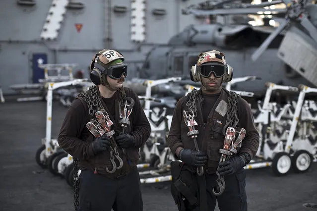 In this Thursday, September 10, 2015 photo, U.S. Navy air wing plane captains carry chains as they pause on the flight deck of the USS Theodore Roosevelt aircraft carrier. Plane captains are identified by wearing brown shirts and are responsible for preparing the aircraft for flight. (Photo by Marko Drobnjakovic/AP Photo)