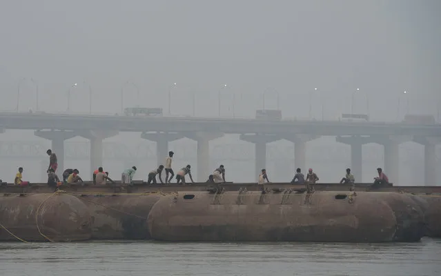 Indian labourers build a floating pontoon bridge over the river Ganges for the upcoming Magh Mela festival in Allahabad on November 9, 2017. The Magh Mela is held every year on the banks of Triveni Sangam – the confluence of the three great rivers Ganga, Yamuna and the mystical Saraswati – in Prayag near Allahabad during the Hindu month of Magh which corresponds to mid January – mid February. (Photo by Sanjay Kanojia/AFP Photo)