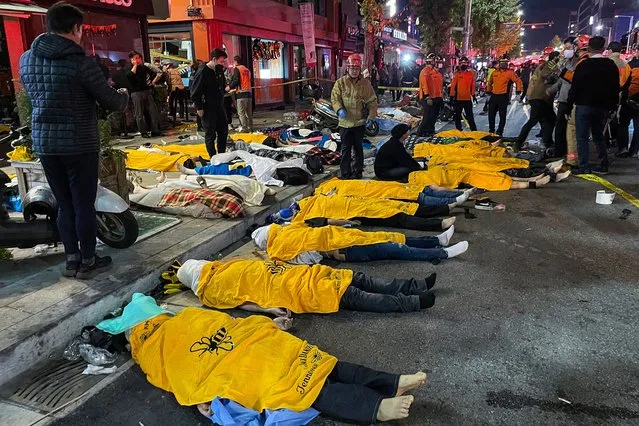 Bodies of victims, believed to have suffered cardiac arrest, are covered  in the popular nightlife district of Itaewon in Seoul on October 30, 2022. (Photo by Yelim Lee/AFP Photo)