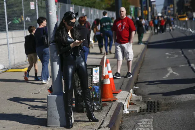 Kim Kwai dressed as the character “Cat Woman”, stands on a street corner outside of the New York's Comic-Con convention, October 9, 2014. (Photo by Shannon Stapleton/Reuters)