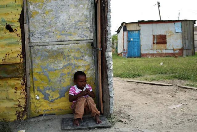 A child sits outside a locked shack in Nkaneng township, Marikana's informal settlement, in Rustenburg, South Africa, April 1, 2014. (Photo by Siphiwe Sibeko/Reuters)