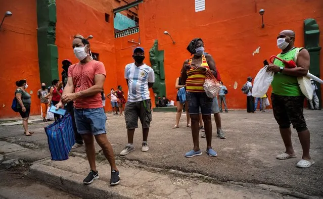 Shoppers wearing protective face masks as a precaution against the spread of the coronavirus, wait their turn to enter a store to buy food, in Havana, Cuba, Wednesday, May 13, 2020. Cuban authorities are requiring the use of masks for anyone outside their homes amid the COVID-19 pandemic. (Photo by Ramon Espinosa/AP Photo)