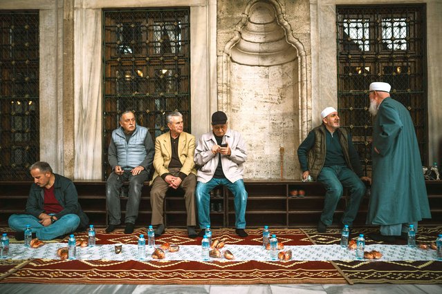 Men sit at the Eyup Sultan Mosque's yard as they wait for the sunset to break the fast, during the Muslim's holy fasting month of Ramadan, in Istanbul on March 14, 2025. (Photo by Ozan Kose/AFP Photo)