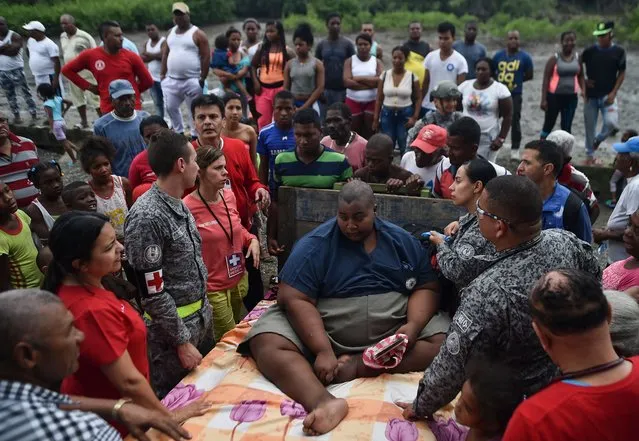 Didier Silva (C), 22, is checked by Air Force doctors on December 2, 2017, in Mosquera, department of Narino, Colombia, before being taken by cart to the helicopter for transfer to Cali. Silva, whose life is in danger because of his weight – over 400 kilos – was transferred in the Air Force's Angel helicopter from the remote village of Mosquera in southwest Colombia to receive medical treatment in the city of Cali. (Photo by Luis Robayo/AFP Photo)