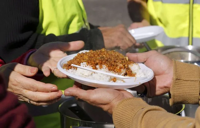 A migrant receives a meal from a member of refugee aid organisations during the distribution of food at the makeshift camp called “The New Jungle” in Calais, France, September 19, 2015. (Photo by Regis Duvignau/Reuters)