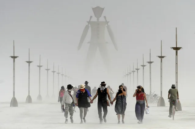 Burning Man participants walk through dust at the annual Burning Man event on the Black Rock Desert of Gerlach, Nev., on Friday, August 29, 2014. Organizers call Burning Man the largest outdoor arts festival in North America, with its drum circles, decorated art cars, guerrilla theatrics and colorful theme camps. (Photo by Andy Barron/AP Photo/The Reno Gazette-Journal)