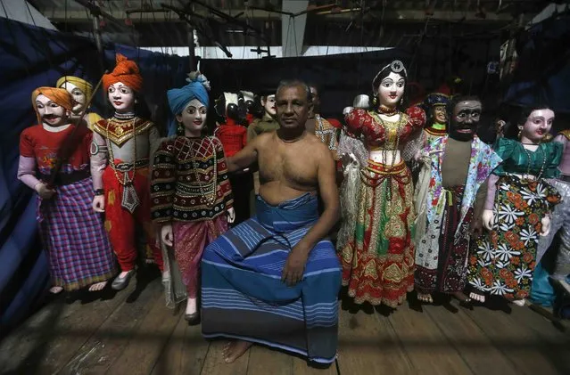 Maestro puppeteer Premin poses for photograph with his Sri Lankan traditional puppets at the backstage before start a puppet show in  Colombo October 18, 2014. Premin comes from a family of puppeteers from the south coastal town of Ambalangoda, which was popular for traditional puppeteers. His grandfather started the family profession of puppeteering in 1922, followed by his father in 1930 and later Premin in 1950. (Photo by Dinuka Liyanawatte/Reuters)