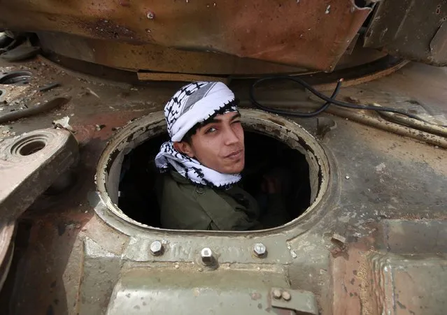 A rebel looks out of a destroyed tank belonging to pro-Gaddafi forces, at the western outskirts of Ajdabiyah, Libya, April 7, 2011. The rebel and his friends were smoking marijuana in the tank. (Photo by Andrew Winning/Reuters)