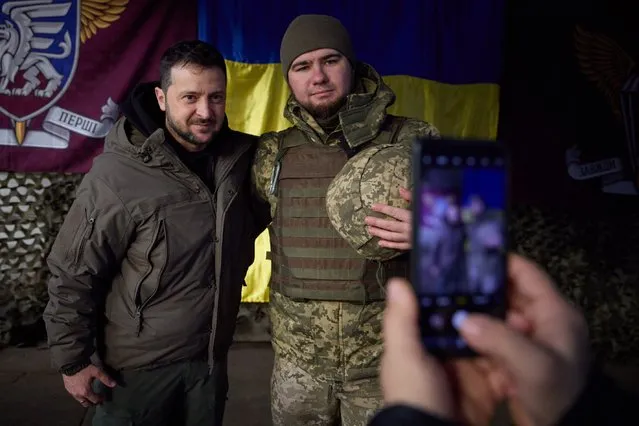 This handout picture taken and released by the Ukrainian Presidential press service on December 6, 2022, shows Ukrainian President Volodymyr Zelensky posing for a picture with a Ukrainian soldier as he visits the Donetsk region, amid the Russian invasion of Ukraine. President Volodymyr Zelensky on Tuesday visited the frontline region of Donetsk in east Ukraine, describing fighting in the area as “difficult” with Russian forces pushing to capture the industrial city of Bakhmut. “From the bottom of my heart, I congratulate you on this great holiday, the Day of the Armed Forces”, said Zelensky, who was later shown meeting soldiers and distributing awards. (Photo by Ukrainian Presidential Press Service)