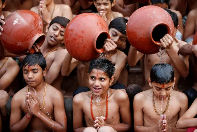 Students react as water from earthen pitchers is poured on them to take a holy bath during a ceremony organised to resemble the annual month-long Hindu religious festival of Magh Mela, held during the Hindu month of Magh, in Ahmedabad, India, January 1, 2018. (Photo by Amit Dave/Reuters)