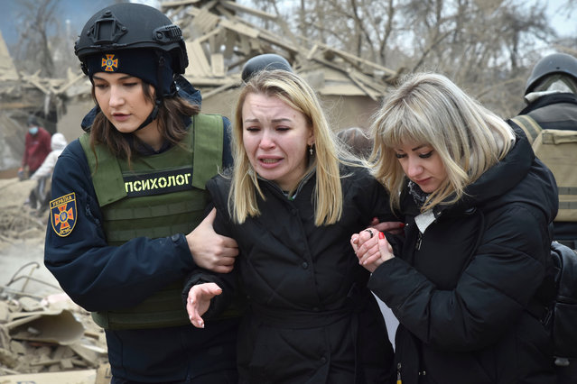An emergency service psychologist, left, comforts a woman at the site of Russia's air attack, in Zaporizhzhia, Ukraine, Friday, March 22, 2024. (Photo by Andriy Andriyenko/AP Photo)
