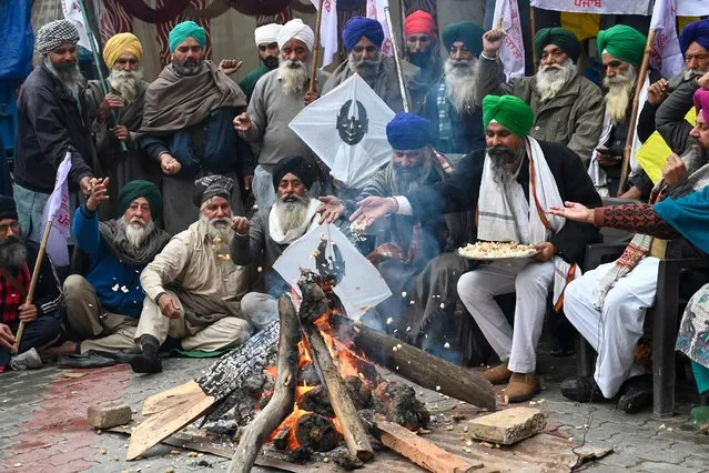 Farmers gather around a bonfire to celebrate Lohri festival while they protest against the central and state government for loan waivers, pensions, crop insurance and minimum support price (MSP), in Amritsar on January 13, 2023. (Photo by Narinder Nanu/AFP Photo)