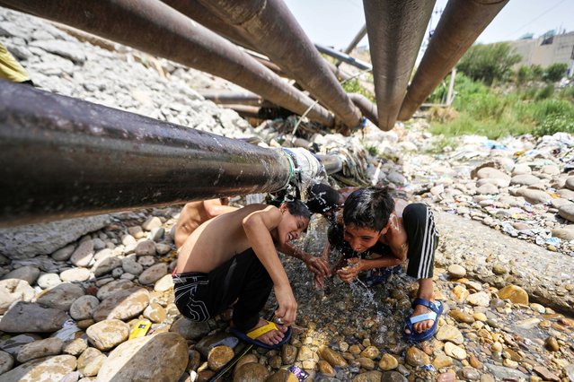 Boys cool off with water leaking from a pipe on a hot summer day in Jammu, India, Tuesday, June 10, 2025. (Photo by Channi Anand/AP Photo)