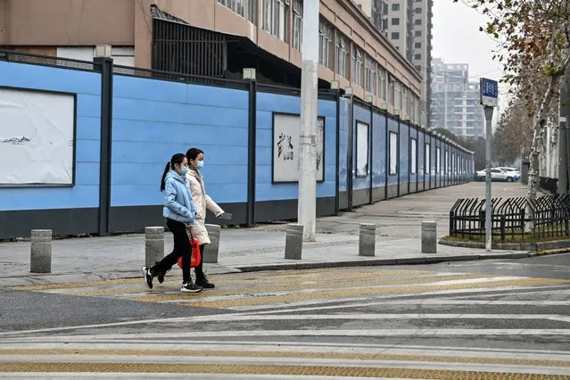 People walk next to the closed Huanan Seafood Wholesale Market, where the Covid-19 coronavirus was first detected, in Wuhan in China's central Hubei province, on January 22, 2023. Residents in Wuhan are marking three years since a once-mysterious virus plunged them into a terrifying lockdown, with their city becoming the epicentre of the Covid-19 epidemic that became global. (Photo by Hector Retamal/AFP Photo)