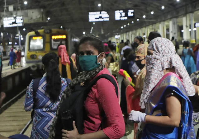 Women passengers wait for a local train in Mumbai, India, Wednesday, October 21, 2020. Indian railways has permitted women passengers to travel in local trains during non-peak hours beginning Wednesday, which otherwise has been running only for essential services. (Photo by Rajanish Kakade/AP Photo)