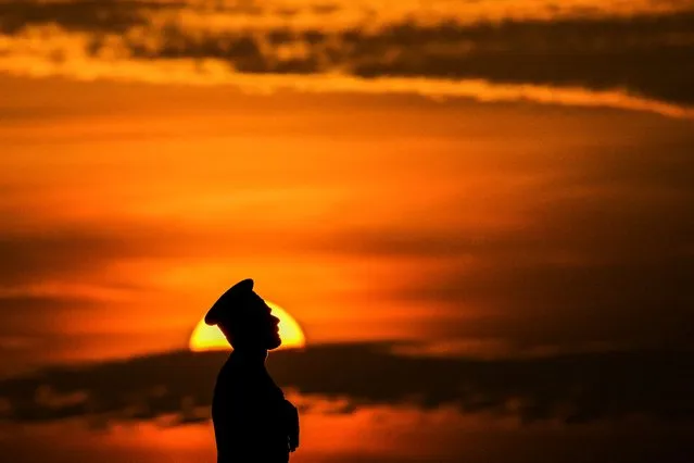 A soldier stands in attention as the national flag is lowered as part of a daily ceremony at the Galle Face Green promenade in Colombo on January 13, 2023. (Photo by Ishara S. Kodikara/AFP Photo)