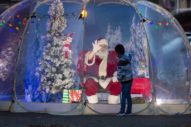 Dan Kemmis, known as the Seattle Santa, high fives a young boy from within a protective plastic bubble in Seattle's Greenwood neighborhood on Sunday, December 6, 2020. Unable to schedule private events due to the coronavirus pandemic, Kemmis is making physically distanced public appearances with some donations benefiting local homeless shelters. (Photo by Paul Christian Gordon/ZUMA Wire/Rex Features/Shutterstock)