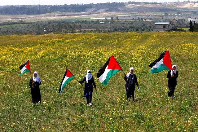 Palestinians hold flags as they mark “Land Day”, an annual commemoration of six Arab citizens of Israel who were killed by Israeli security forces during demonstrations over land confiscations in 1976, in the southeast of Gaza City on March 30, 2023. (Photo by Ibraheem Abu Mustafa/Reuters)