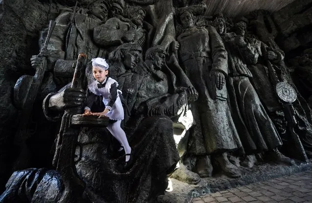 A girl climbs on a sculptural composition after a cadets parade at the WWII open-air museum in Kiev on May 4, 2018. Some 700 cadets of the Ukrainian military lyceums take part in the parade and memorial ceremony marking Victory Day. (Photo by Sergei Supinsky/AFP Photo)