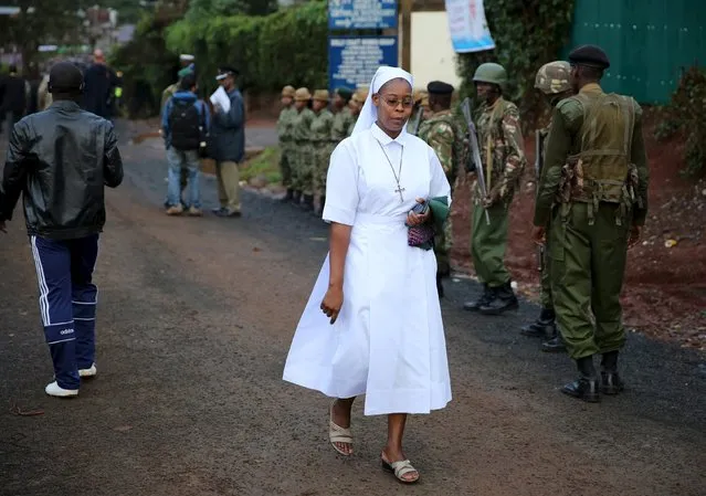 A nun passes by a group of soldiers before Pope Francis' arrival at the Kangemi slum on the outskirts of Kenya's capital Nairobi, November 27, 2015. (Photo by Goran Tomasevic/Reuters)