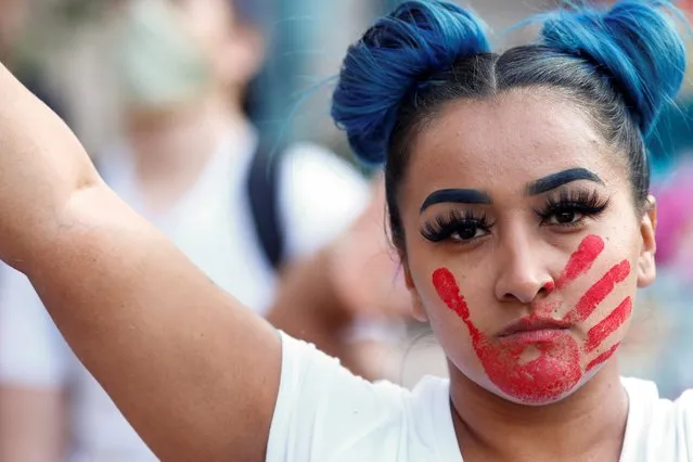 A woman with a red hand painted on her face, which calls attention to the high rates of indigenous women who are murdered or missing, raises a sign in solidarity with the Black Lives Matter Movement at a protest against racial inequality in the aftermath of the death in Minneapolis police custody of George Floyd, in Denver, Colorado, June 3, 2020. (Photo by Kevin Mohatt/Reuters)