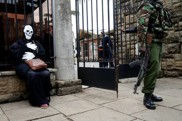 A Kenyan policeman stands guard next to an environmental activist wearing a costume during a protest against a planned coal plant outside Parliament house in Nairobi, Kenya, June 5, 2018. (Photo by Baz Ratner/Reuters)