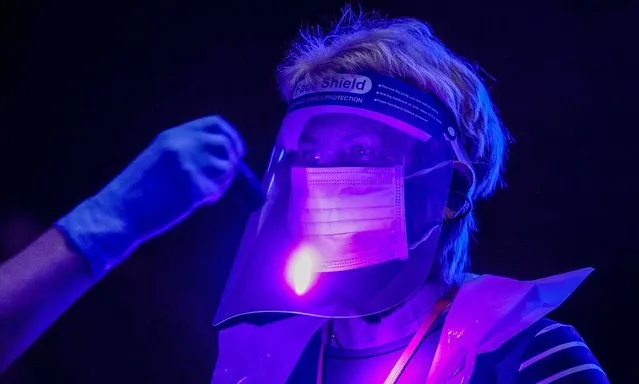 Volunteers are illuminated by ultra violet light to demonstrate how bacteria and contamination can be spread as they are trained by St John Ambulance instructors to administer Covid-19 vaccines at Manchester United Football Club on January 30, 2021 in Manchester, England. The St John Ambulance volunteer-based organisation is training more than 30,000 volunteers to join the UK's covid-19 vaccination campaign. Volunteer vaccinators complete 21.5 hours of training over four weeks, a blend of online and in-person learning. St John Ambulance's highly skilled volunteers have been supporting the NHS throughout the COVID-19 pandemic. (Photo by Christopher Furlong/Getty Images)