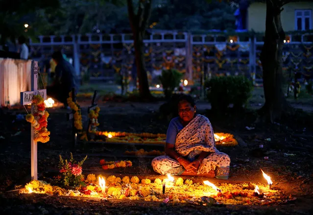 A woman prays beside the grave of her relative at a cemetery during the observance of All Souls Day in Mumbai, India November 2, 2016. (Photo by Danish Siddiqui/Reuters)