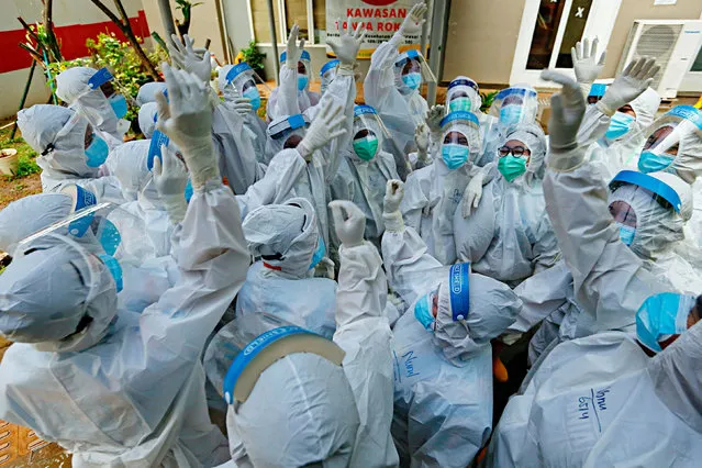 Healthcare workers wearing personal protective equipment (PPE) react as they prepare to treat patients at the emergency hospital for coronavirus disease (COVID-19) in Athletes Village, Jakarta, Indonesia on January 26, 2021. (Photo by Ajeng Dinar Ulfiana/Reuters)
