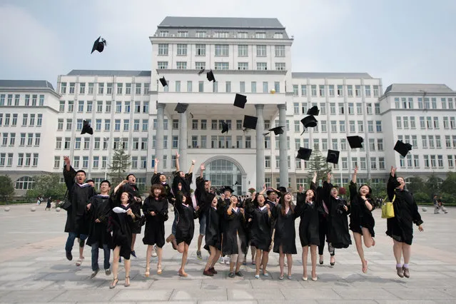 Students throw their caps in the air as friends take photos following a graduation ceremony at the private Kade College Capital Normal University on the outskirts of Beijing on June 26, 2013. Despite a boom in student numbers in recent years, many graduates from second and third-tier institutions face considerable employment uncertainty in an economy largely fuelled by a blue-collar workforce. (Photo by Ed Jones/AFP Photo)