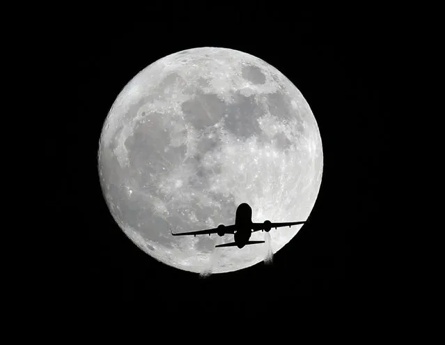 An American Airlines passenger plane passes in front of the moon, as seen from Whittier, Calif., Sunday, November 13, 2016. Monday morning's supermoon will be the closet a full moon has been to the Earth since Jan. 26, 1948. (Photo by Nick Ut/AP Photo)
