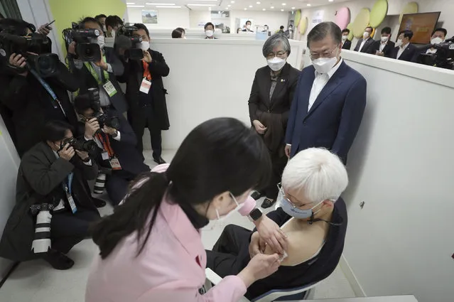 South Korean President Moon Jae-in, top right, watches a doctor receives a shot of AstraZeneca vaccine at a public health center in Seoul, South Korea, Friday, February 26, 2021. South Korea on Friday administered its first available shots of coronavirus vaccines to people at long-term care facilities, launching a mass immunization campaign that health authorities hope will restore some level of normalcy by the end of the year. (Photo by Choe Jae-koo/Yonhap via AP Photo)