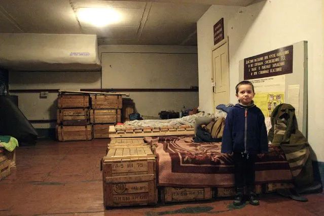 A boy poses for a picture inside a bomb shelter on the outskirts of Donetsk, January 28, 2015. Forty-four locals seeking protection from the shelling in the region have lived inside this shelter for over than a month, the residents said. (Photo by Alexander Ermochenko/Reuters)