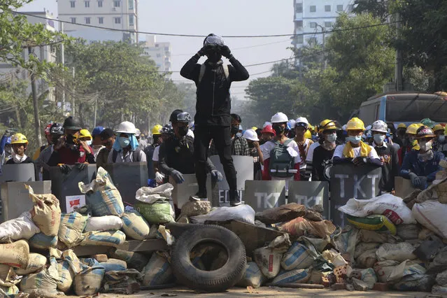Protesters take positions behind a barricades as police gather in Yangon, Myanmar, Sunday, March 7, 2021. The escalation of violence in Myanmar as authorities crack down on protests against the Feb. 1 coup is raising pressure for more sanctions against the junta, even as countries struggle over how to best sway military leaders inured to global condemnation. (Photo by AP Photo/Stringer)
