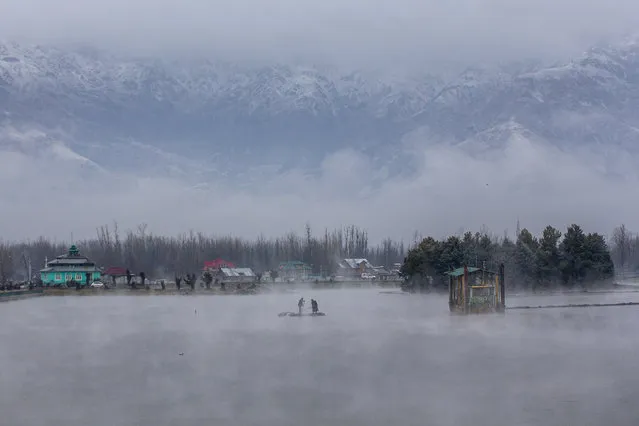 Kashmiri men row their makeshift raft made of plastic pipes on the Dal Lake after a brief spell of fresh snowfall on the outskirts of Srinagar, Indian controlled Kashmir, Saturday, February 27, 2021. (Photo by Dar Yasin/AP Photo)