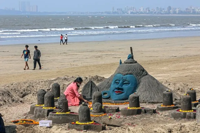 Devotees perform rituals to a sand sculpture of Hindu god Lord Shiva, made by Indian sand artist Laxmi Gaud for visitors and tourists to see on the occasion of Maha Shivaratri at the Juhu beach in Mumbai, India, 11 March 2021. The Maha Shivaratri festival is celebrated by Hindus in honor of Lord Shiva with ritual bathing of Shivalingams and prayers. According to one of the most popular legends Shivaratri is the wedding day of Lord Shiva and Parvati. (Photo by Divyakant Solanki/EPA/EFE)