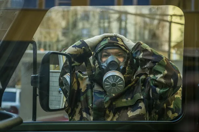 A Hungarian soldier wearing hasmat prepares to disinfect a combined kindergarten and elementary school in an effort to curb the spread of the pandemic of the new coronavirus in Budapest, Hungary, Wednesday, March 17, 2021. (Photo by Zoltan Balogh/MTI via AP Photo)