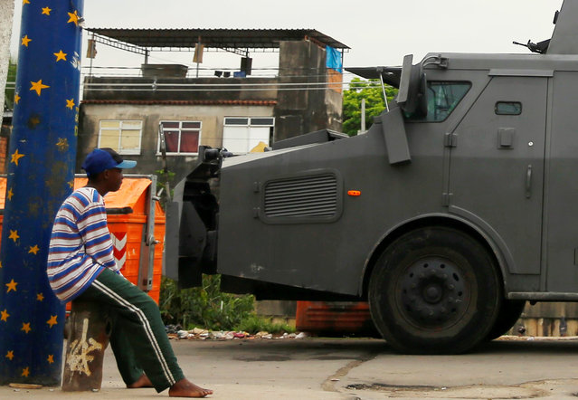 A man sits as a police armored vehicle is seen during an operation against drug dealers in City of God or City of God slum in Rio de Janeiro, Brazil, November 23, 2016. (Photo by Ricardo Moraes/Reuters)