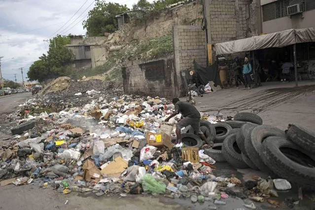A man walks over accumulated garbage in Port-au-Prince, Haiti, Friday, June 2, 2023. (Photo by Ariana Cubillos/AP Photo)