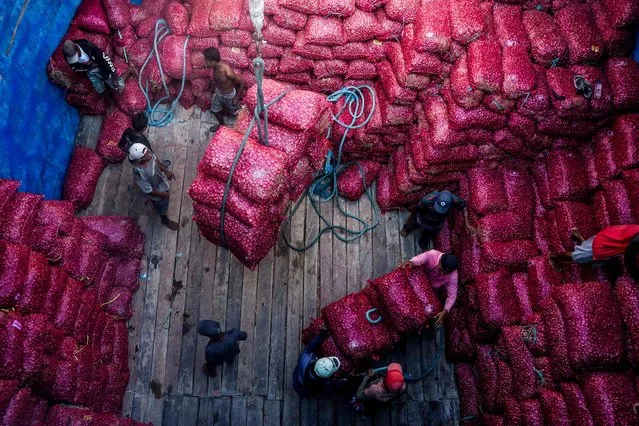 Workers move sacks of shallots from a transport ship at Paotere People's Port, in Makassar on July 21, 2023. (Photo by Indra Abriyanto/AFP Photo)