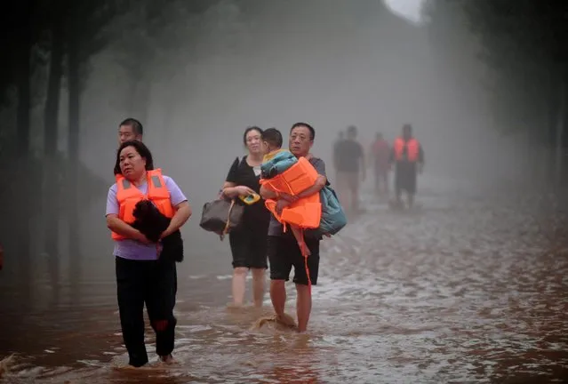 Residents wade through floodwaters following heavy rainfall in Zhuozhou, Hebei province, China on August 2, 2023. (Photo by cnsphoto via Reuters)