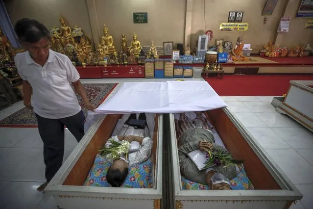 Buddhist devotees lie inside coffins during a “live funeral” ritual at Bangna Nai temple in Bangkok, Thailand, 13 February 2021. (Photo by Diego Azubel/EPA/EFE)