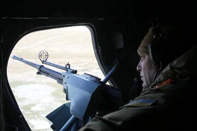 A member of the Ukrainian armed forces keeps his weapon at the ready as he looks out of a helicopter while flying above Kharkiv region, February 24, 2015. REUTERS/Valentyn Ogirenko (UKRAINE - Tags: MILITARY CONFLICT CIVIL UNREST TRANSPORT)
