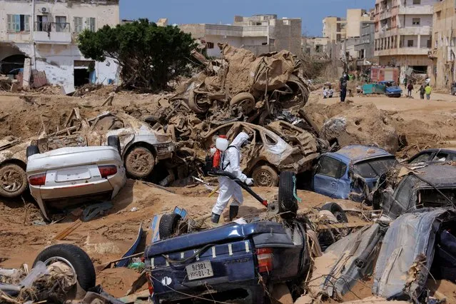 A sanitation worker disinfects rubble, amid rising concerns of spread of infectious diseases, as dead bodies started to decompose, following fatal floods in Derna, Libya on September 17, 2023. (Photo by Amr Alfiky/Reuters)