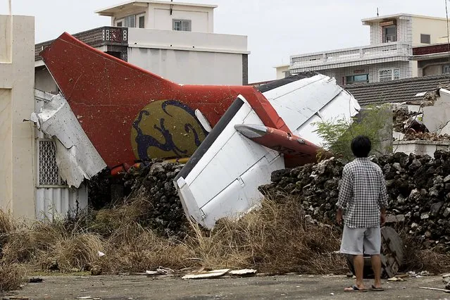 A man stands in his backyard and looks at the wreckage of a TransAsia Airways turboprop plane that crashed on Taiwan's offshore island Penghu in this July 24, 2014 file photo. TransAsia Airways should review its safety protocols, pilot training programme and hiring practices to reduce “imminent risks”, Taiwan's aviation safety agency said on January 29, 2016. (Photo by Pichi Chuang/Reuters)