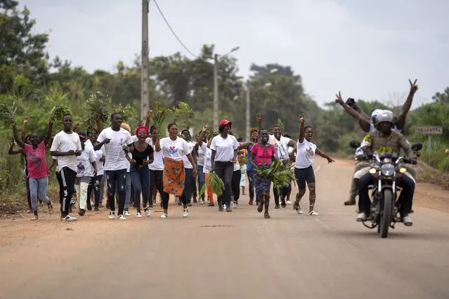 People sing as they walk on the road toward the former Ivorian president Laurent Gbagbo's hometown celebrating his return to the country, in Mama, Ivory Coast, Saturday, June 19, 2021. (Photo by Leo Correa/AP Photo)