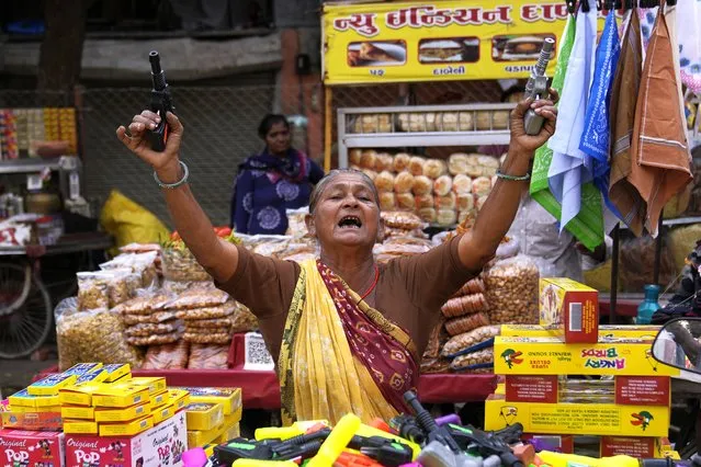 A street vendor woman selling firecracker toy guns tries to attract customers in Ahmedabad, India, Sunday, November 5, 2023. (Photo by Mahesh Kumar A./AP Photo)